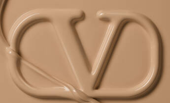 Close-up of a creamy, beige substance forming the letters "CD," resembling a cosmetic product.