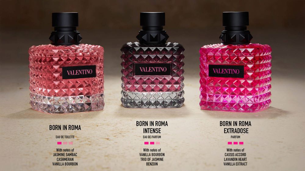 Three scent bottles from Valentino's "Born in Roma" collection are displayed, featuring distinct pink and clear designs. Each bottle is labeled with its specific variant: "Born in Roma Eau de Toilette," "Born in Roma Intense," and "Born in Roma Extradose," along with their fragrance notes.