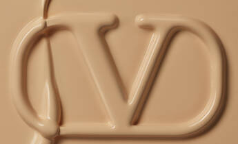 A close-up image of a smooth, beige liquid that has the letters "CD" artistically formed within it, resembling a cosmetic or skincare product.