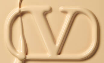 Close-up of a creamy, beige substance forming the letters "VD" in a smooth, flowing style.