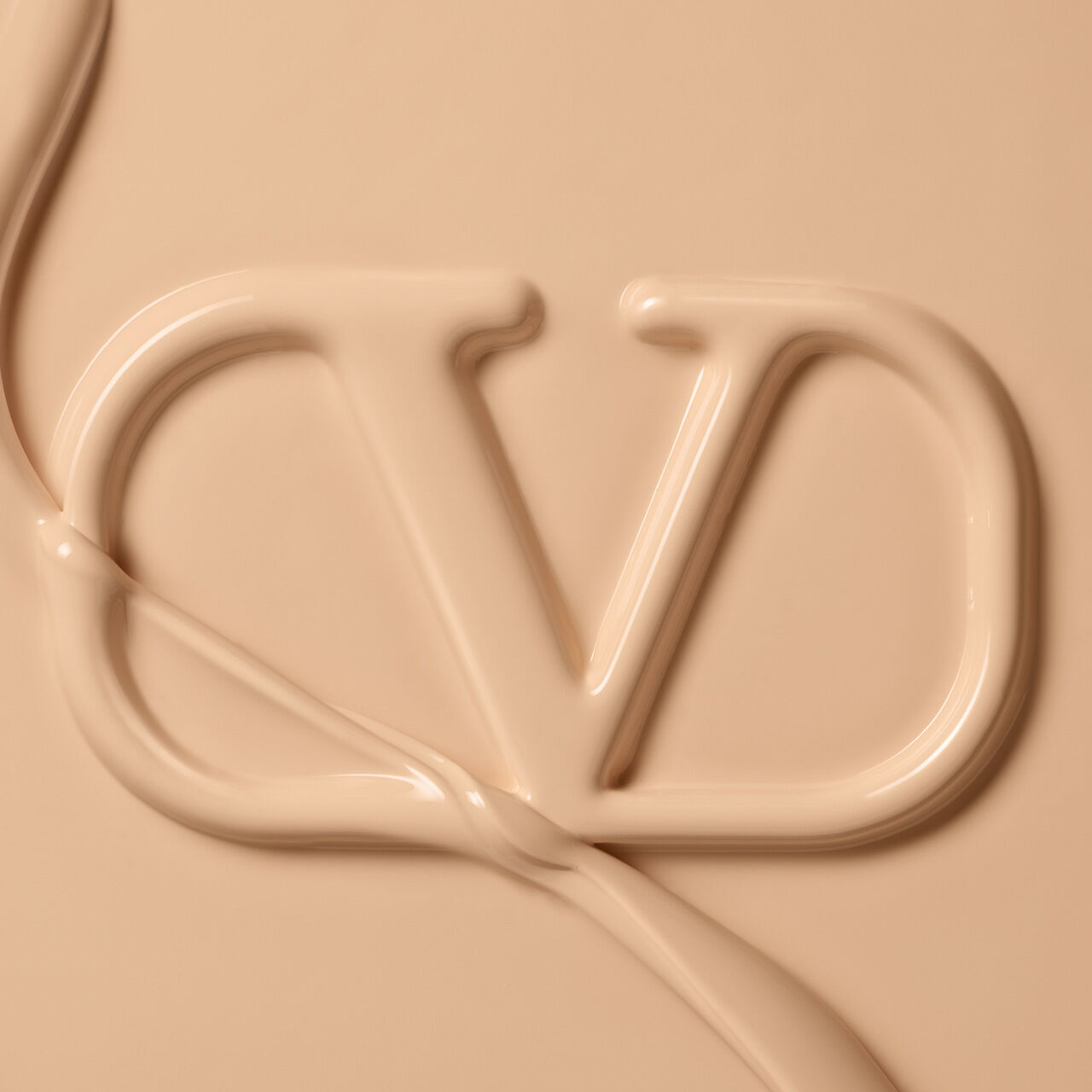 A close-up of a fluid, creamy substance shaped into the letters "CD" against a neutral beige background.