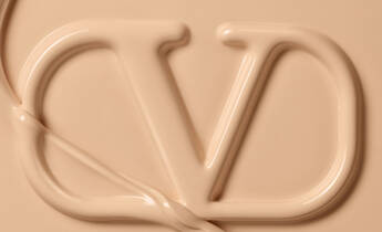 A close-up of a fluid, creamy substance shaped into the letters "CD" against a neutral beige background.