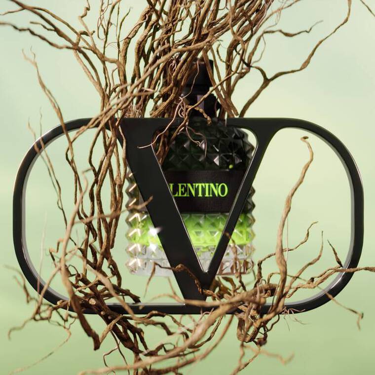 A stylized bottle of Valentino perfume nestled among intricate twisted branches, against a soft green background.