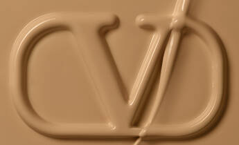Close-up of a smooth, creamy surface featuring an embossed logo with stylized letters "C" and "D." The background is a warm beige color.