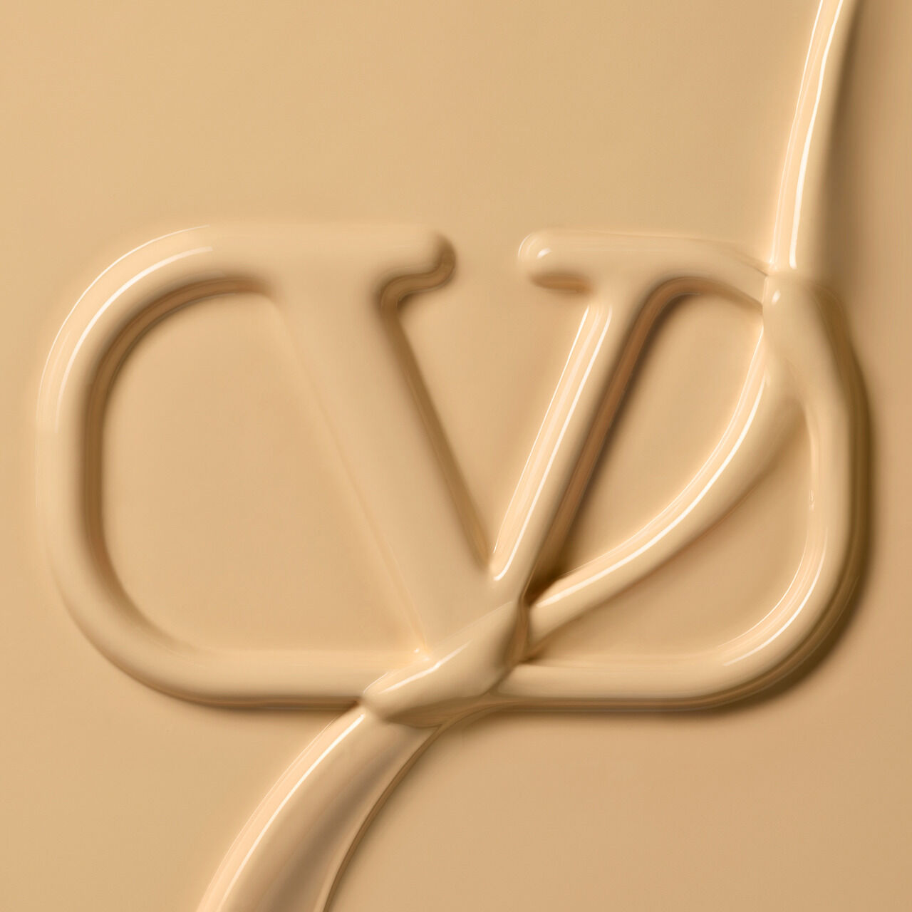 A creamy, beige substance shaped into the letters "CD" against a smooth background.