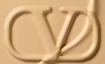A creamy, beige substance shaped into the letters "CD" against a smooth background.
