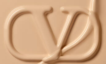 A close-up of creamy beige product with an embossed letter "Y" and a fluid line swirling around it, creating a textured appearance.