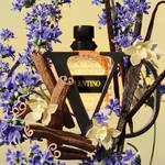 A stylish perfume bottle surrounded by vibrant blue flowers, delicate yellow blooms, and decorative twigs, creating an elegant, floral arrangement.