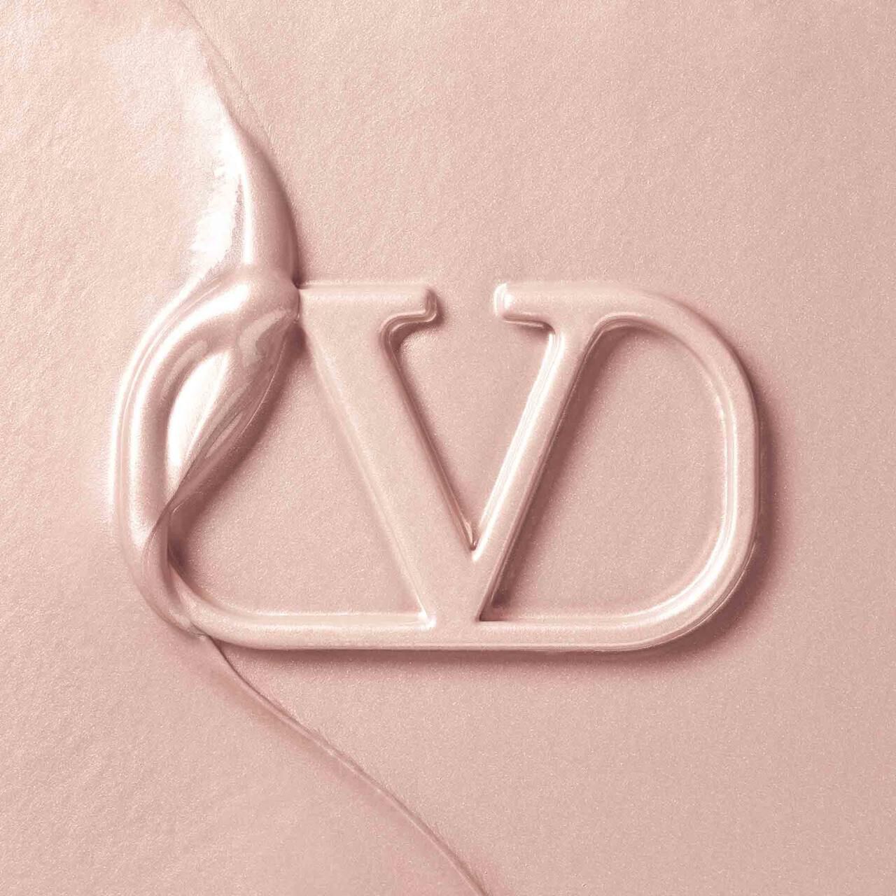 Close-up of a creamy texture with a stylized "VD" logo partially embedded in it, displaying a soft, light pink color.