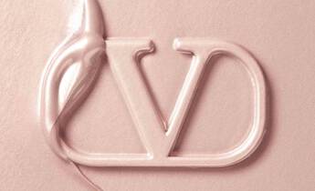 Close-up of a creamy texture with a stylized "VD" logo partially embedded in it, displaying a soft, light pink color.