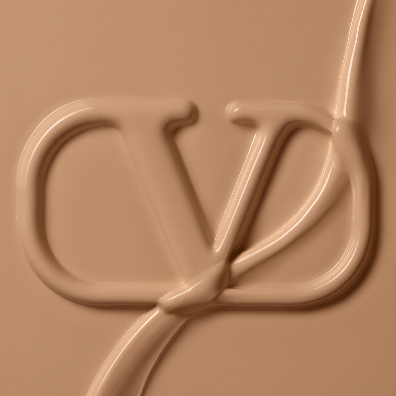 Close-up of a smooth, beige creamy texture with a stylized logo embossed into it, resembling the letters "CD."
