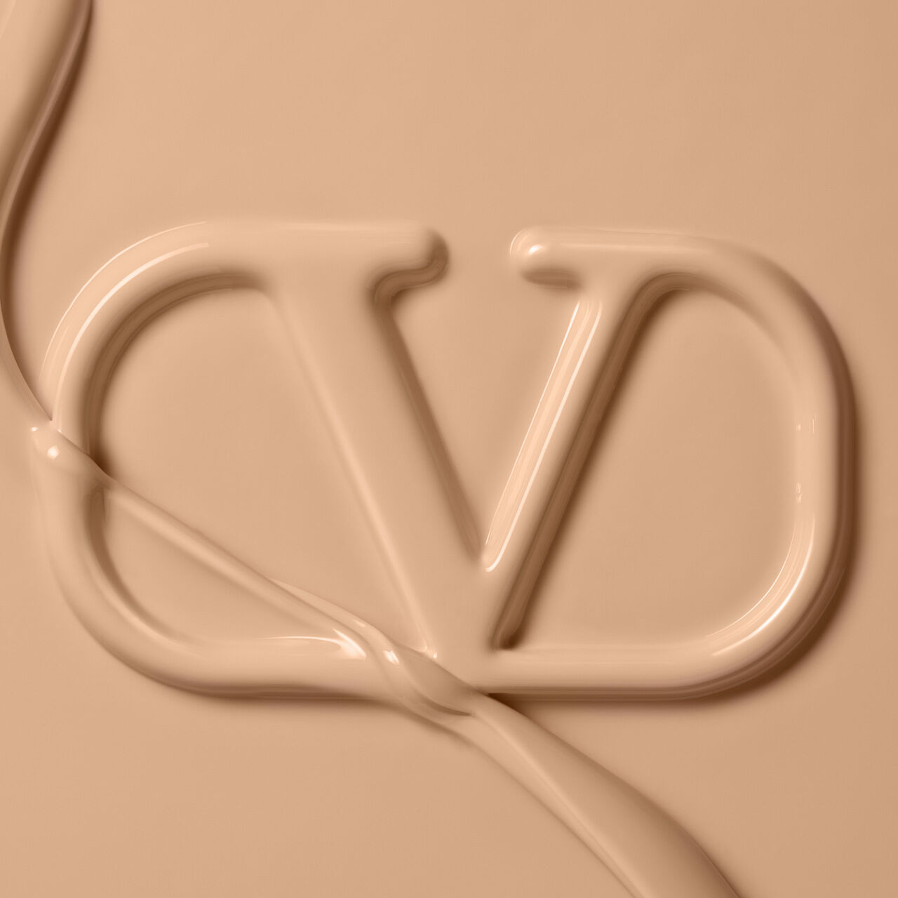 Close-up of a creamy beige substance forming the letters "VD," with a smooth, flowing texture.