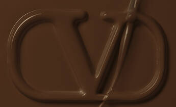 A smooth, dark brown surface featuring an embossed logo that resembles the letters "VD."