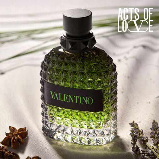 A stylish green Valentino perfume bottle, artistically lit on a textured surface, surrounded by lavender and spices.