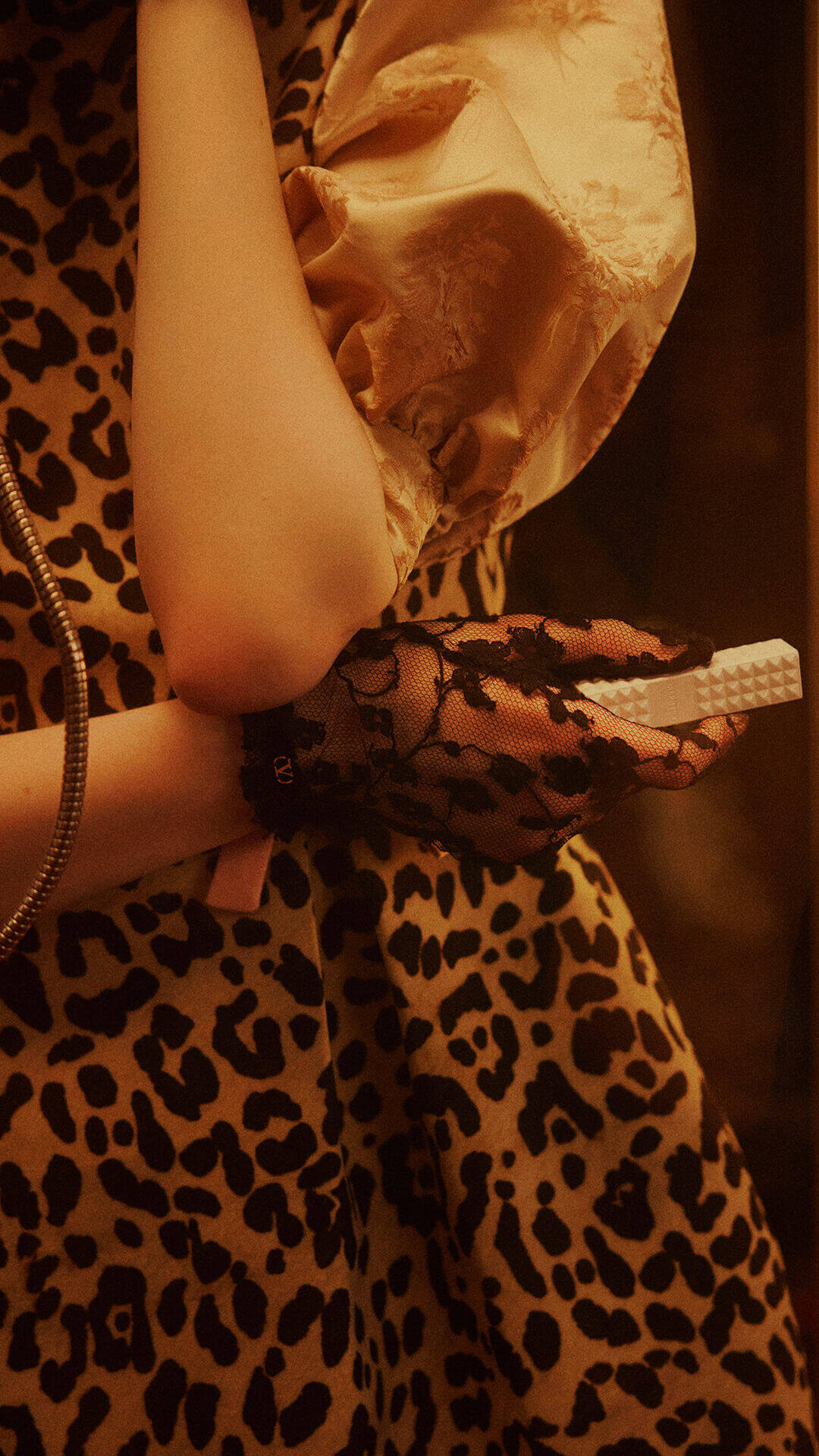 A woman wearing black lace-patterned gloves held a SPIKE VALENTINO IVORY, pressing the keys of a vintage telephone.
