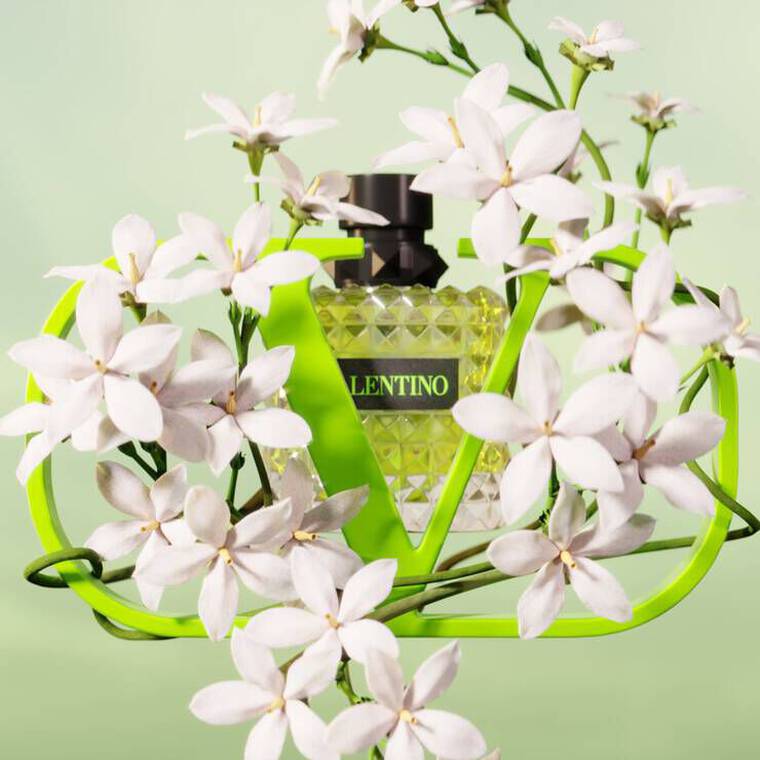 A vibrant green perfume bottle is nestled among delicate white flowers against a soft green background.
