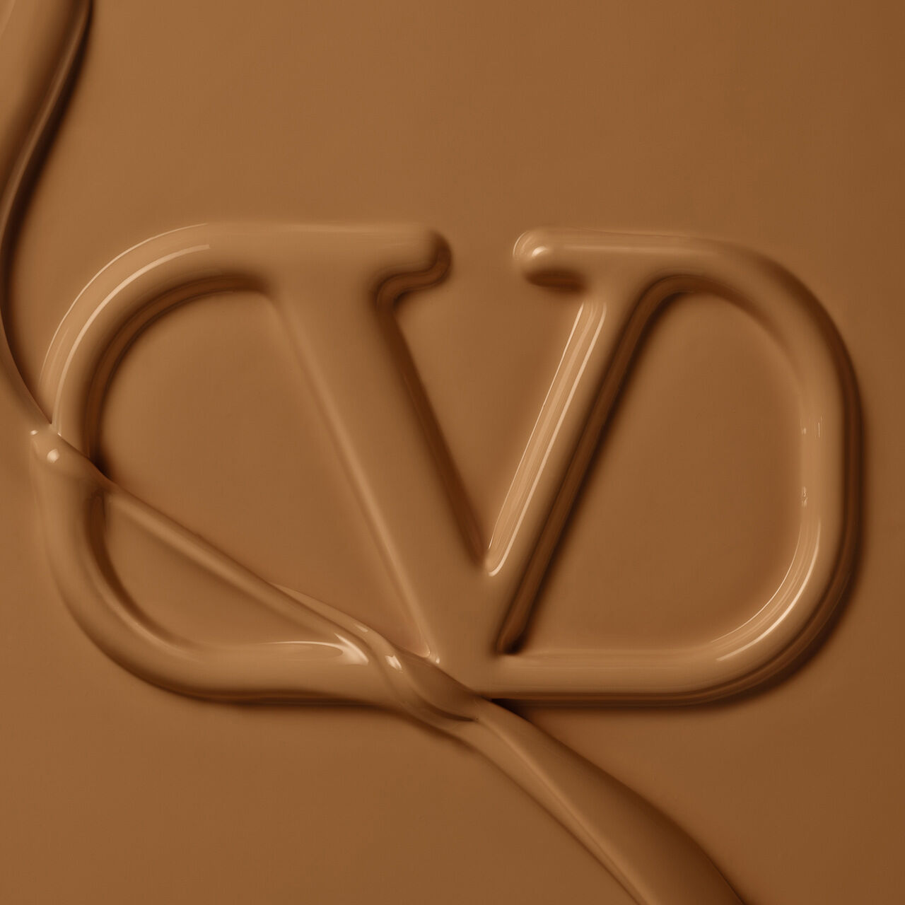 A close-up of a fluid, chocolate-colored material forming the letters "CD." The texture is smooth and glossy, with a slight sheen.