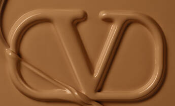 A close-up of a fluid, chocolate-colored material forming the letters "CD." The texture is smooth and glossy, with a slight sheen.