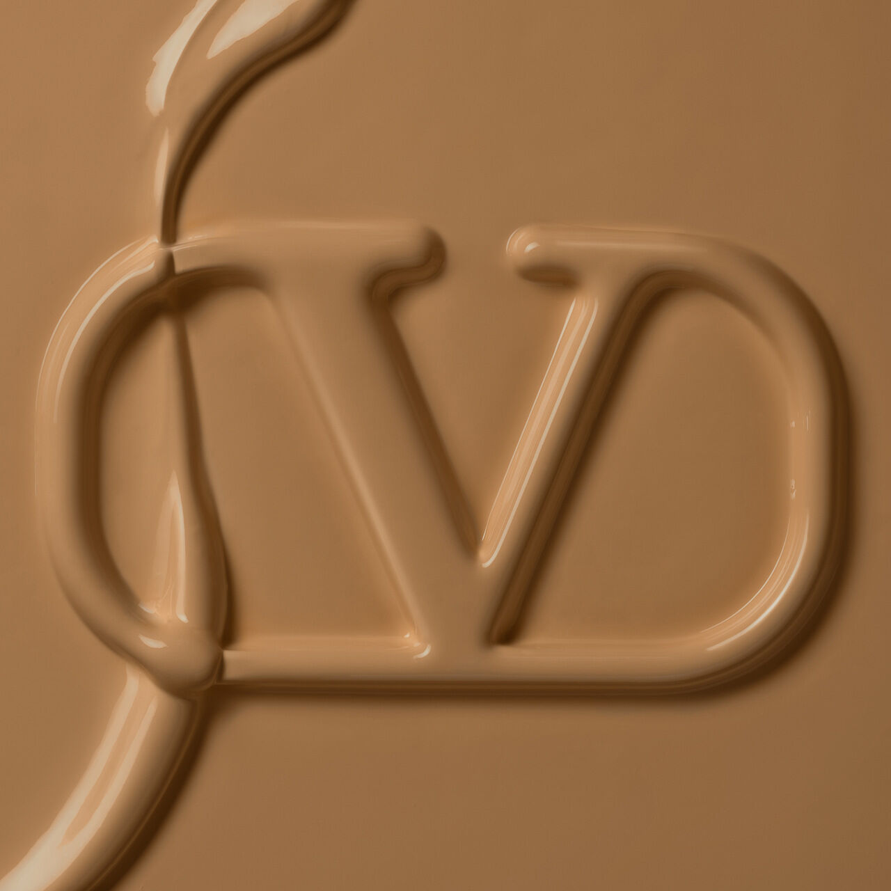 Close-up of a smooth, creamy texture in a warm beige shade, with a stylized logo 'JD' prominently featured in the center.