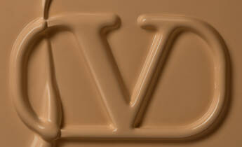 Close-up of a smooth, creamy texture in a warm beige shade, with a stylized logo 'JD' prominently featured in the center.