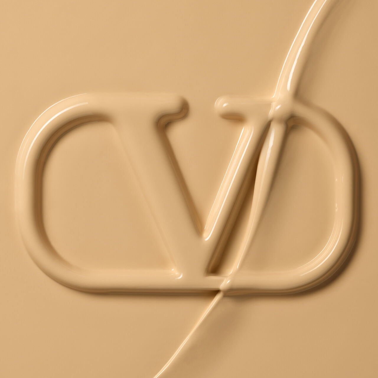Close-up of a creamy, beige substance with an embossed logo featuring the letters "CD."