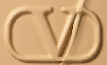Close-up of a creamy, beige substance with an embossed logo featuring the letters "CD."