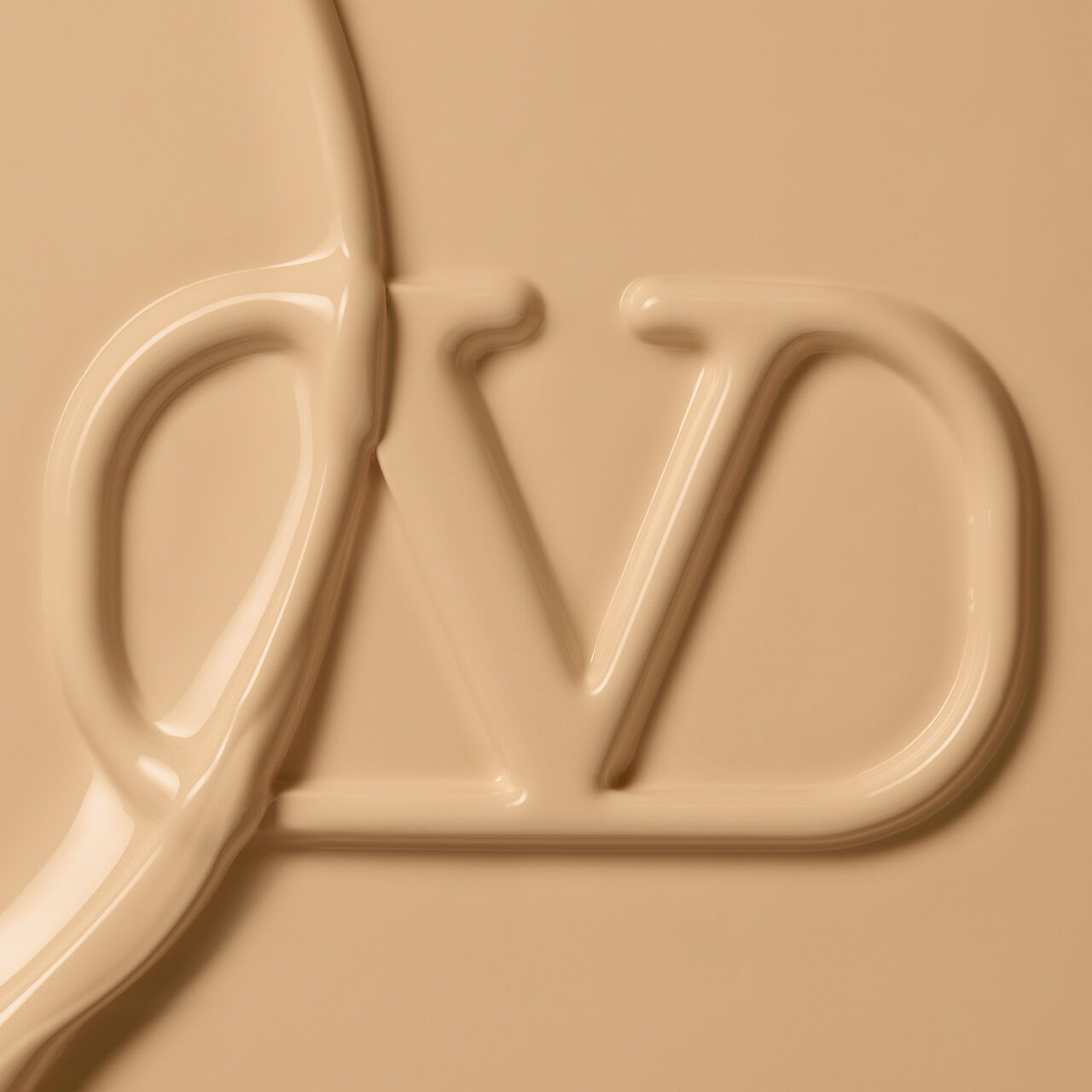 Close-up of a creamy, beige-colored substance forming the letters "VD" in a smooth, flowing texture.