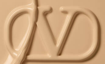 Close-up of a creamy, beige-colored substance forming the letters "VD" in a smooth, flowing texture.