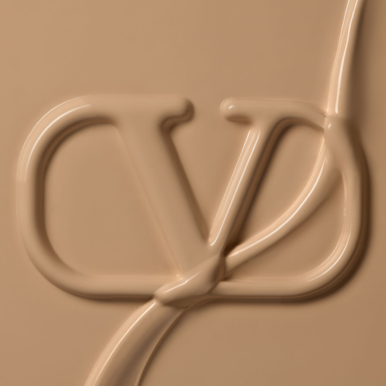 A close-up image of a creamy, beige substance forming the letters "CD" in an elegant script, creating a smooth and artistic texture.