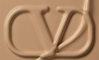 A close-up image of a creamy, beige substance forming the letters "CD" in an elegant script, creating a smooth and artistic texture.