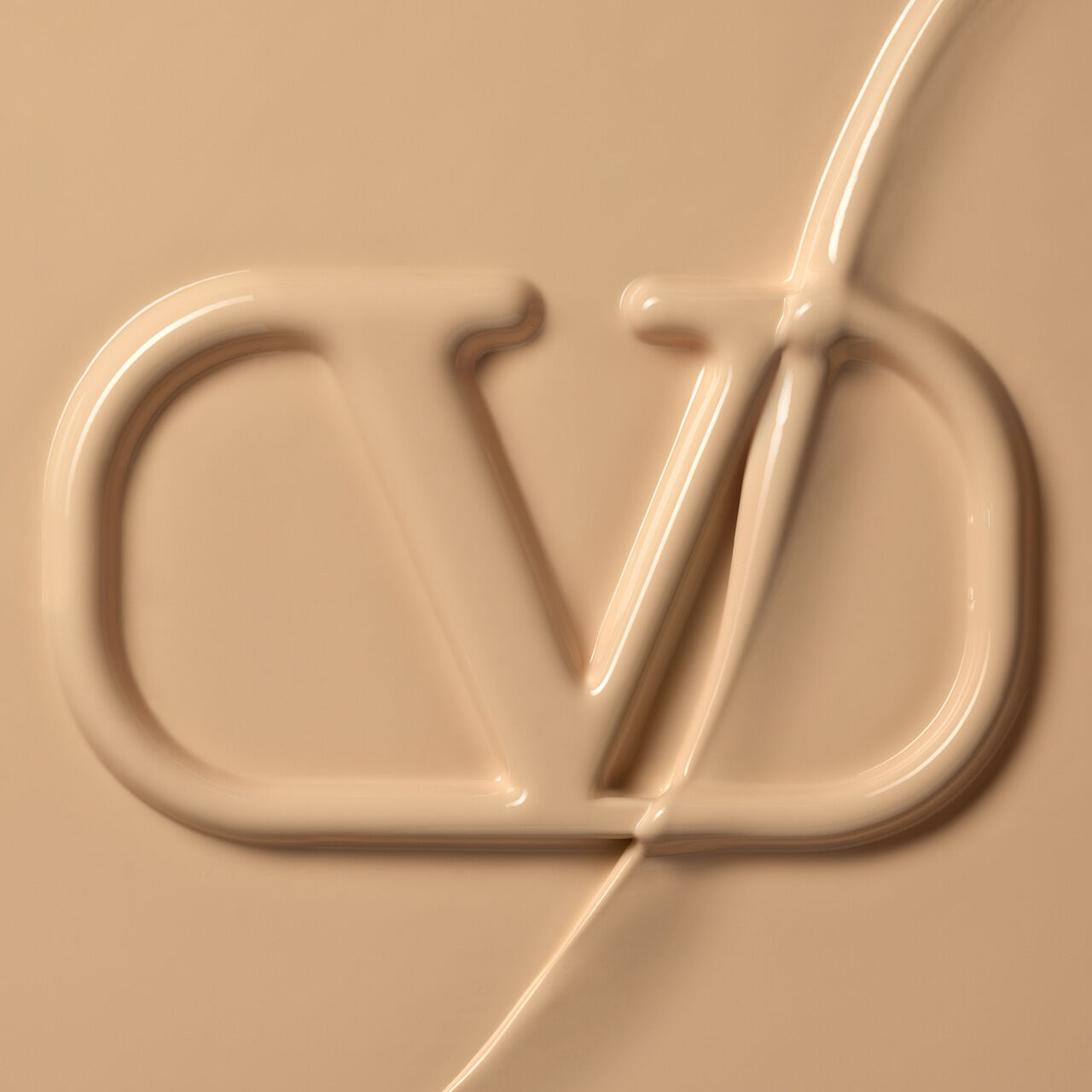 Close-up view of a smooth, beige cream or foundation featuring a prominent embossed logo that reads "CD."