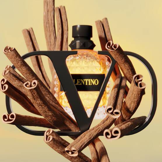 A stylish perfume bottle with a geometric design is surrounded by twisting branches, creating a modern and artistic display. The bottle features the brand name "Valentino" prominently on its label.