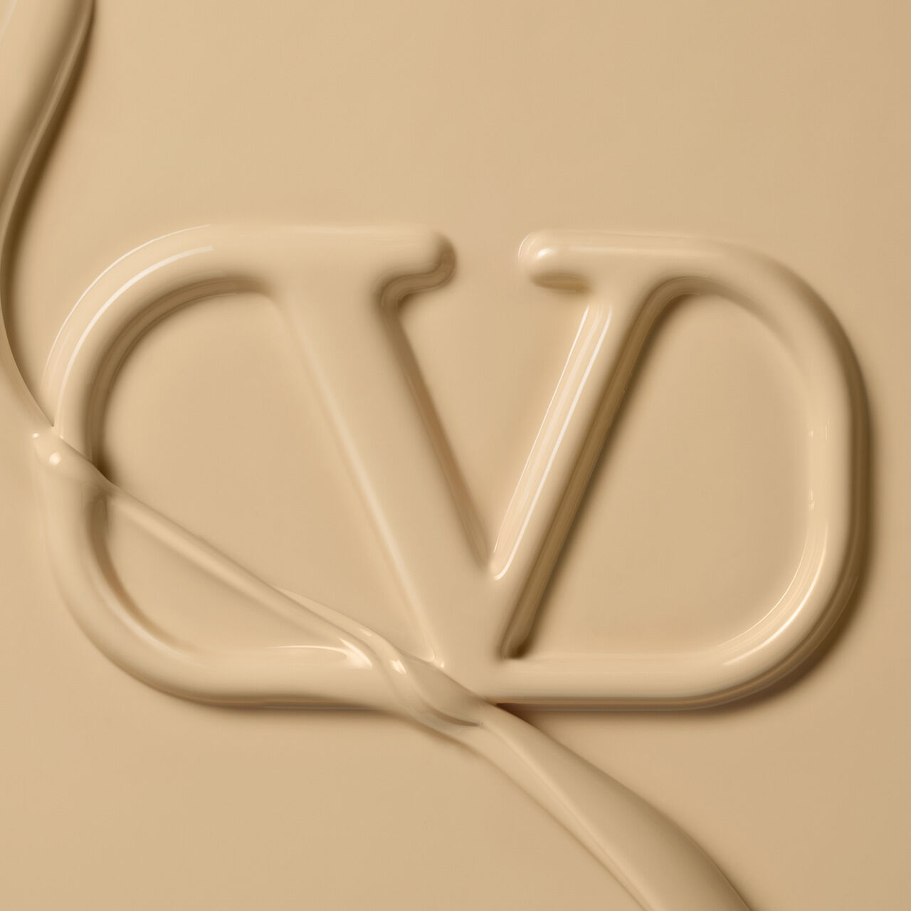 A close-up image of a smooth, creamy texture forming the letters "DV" against a beige background.