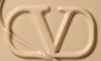A close-up image of a smooth, creamy texture forming the letters "DV" against a beige background.
