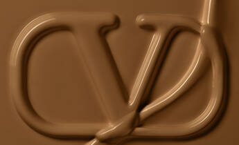 The image features a smooth, chocolate-like texture with a stylized logo subtly integrated into the design, resembling a blend of letters against a warm brown background.