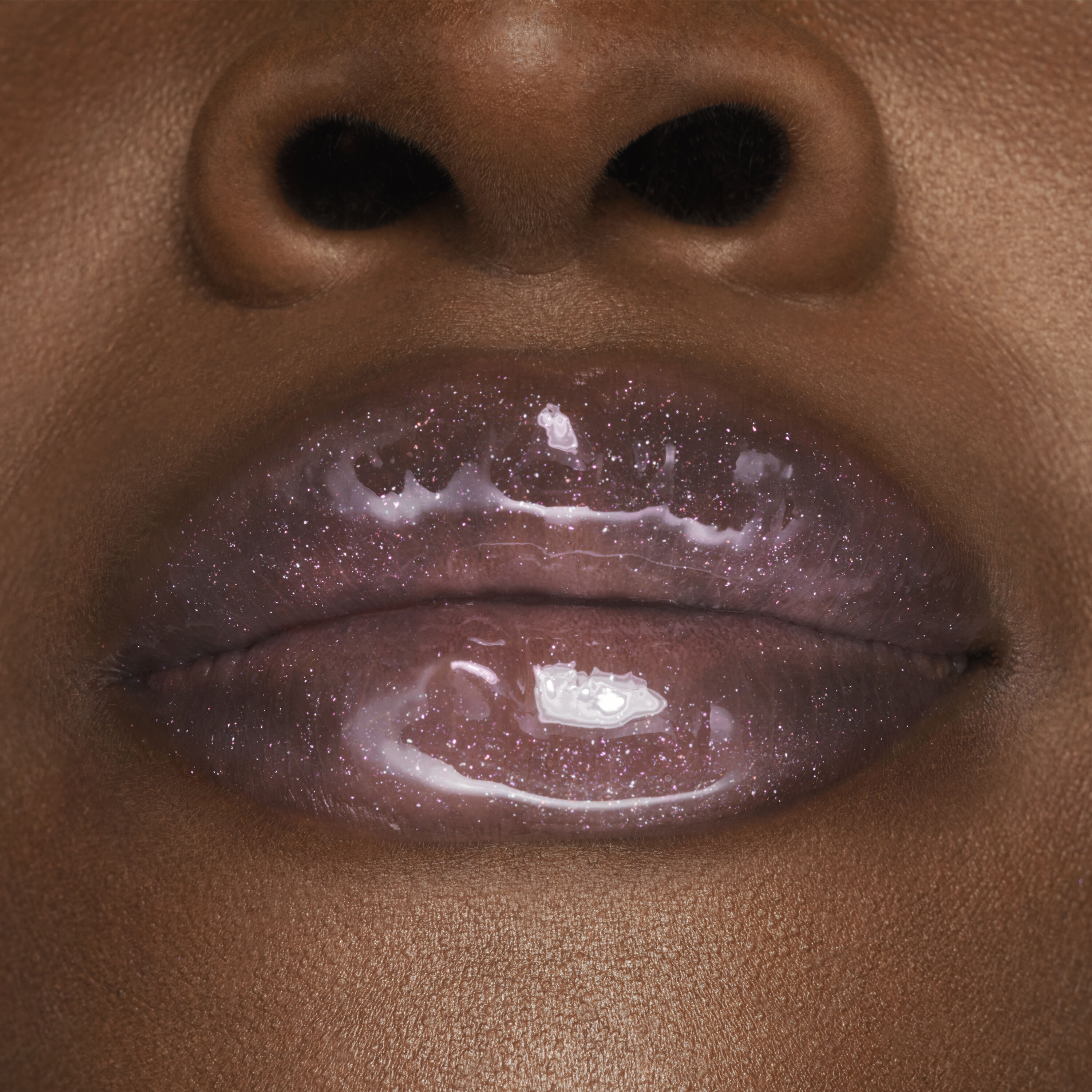Close-up of glossy, sparkly lips, showcasing a shimmering lip gloss against rich brown skin.