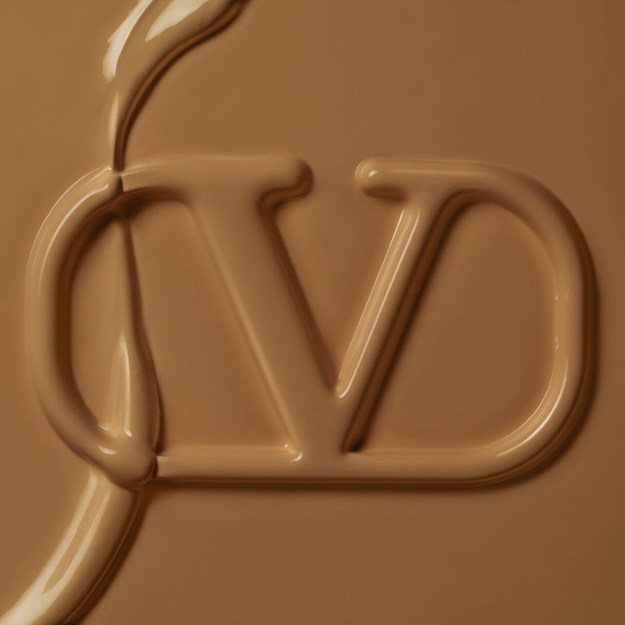 Close-up of a glossy, caramel-colored surface featuring a stylized "JD" logo embossed in the material.