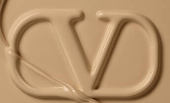 A close-up of a creamy beige surface featuring the stylized letters "VD" formed by a smooth, flowing substance.