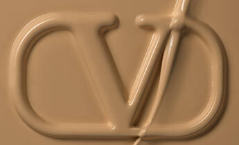 Close-up of a textured surface featuring a stylized logo, embossed in a creamy beige color.