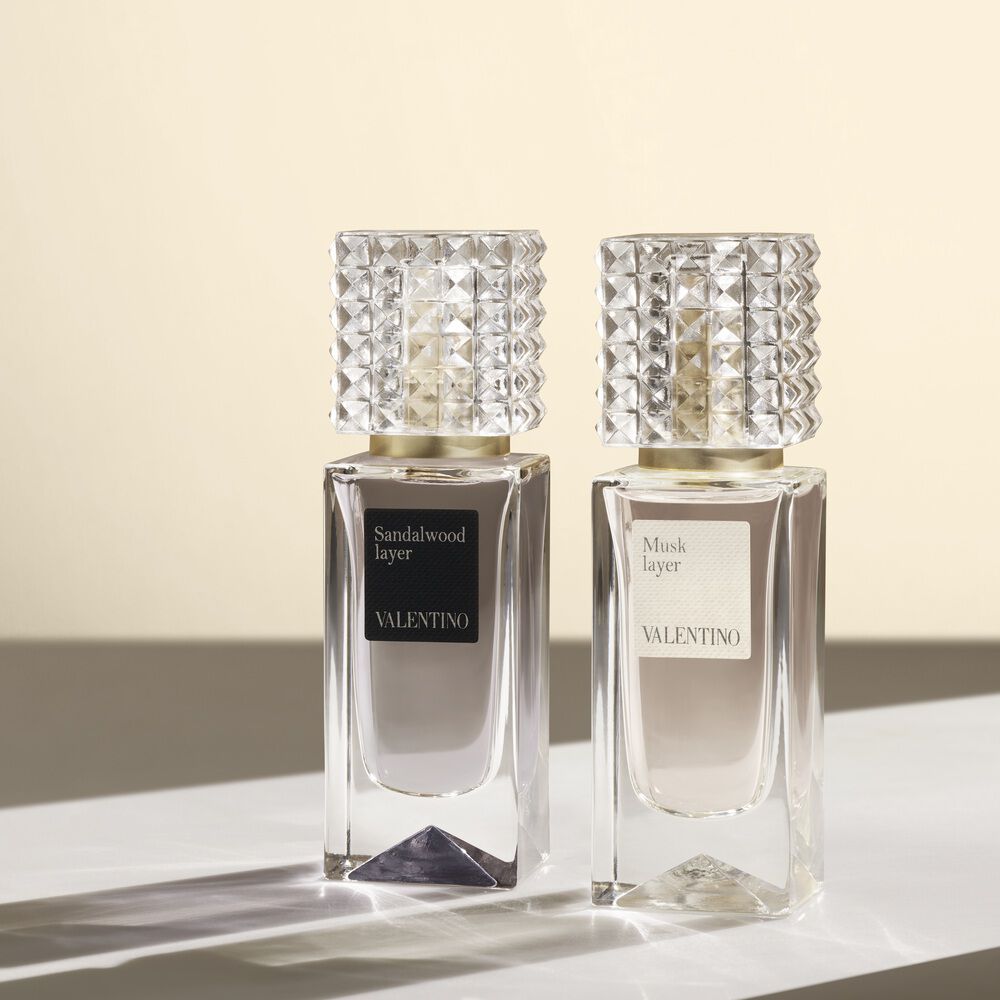 Deux flacons de parfum Valentino, nommes Sandalwood Layer et Musk Layer, presentes sur une surface claire