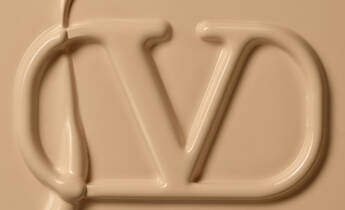 An abstract close-up of a creamy, beige substance forming the letters "JD" in a smooth, fluid style.