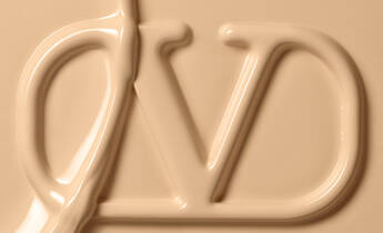 Close-up of a smooth, creamy texture forming the letters "DV" in a light beige color.