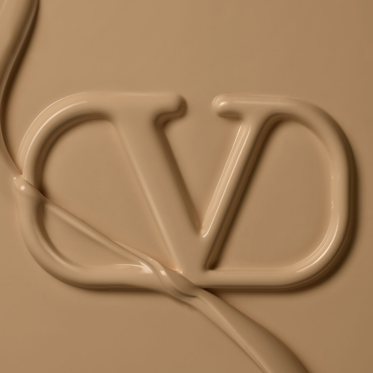 A close-up of a textured beige surface featuring the letters "V" and "D" elegantly formed from a cream-like substance.