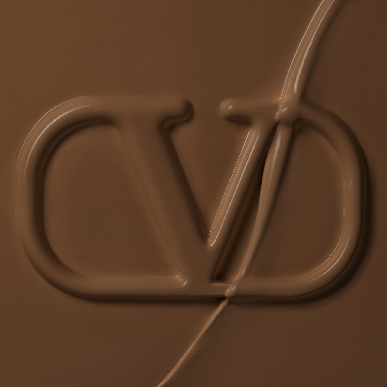 Close-up of a smooth, creamy chocolate surface with a stylized logo imprinted in it.