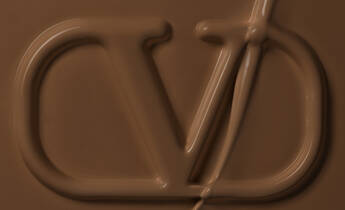 Close-up of a smooth, creamy chocolate surface with a stylized logo imprinted in it.