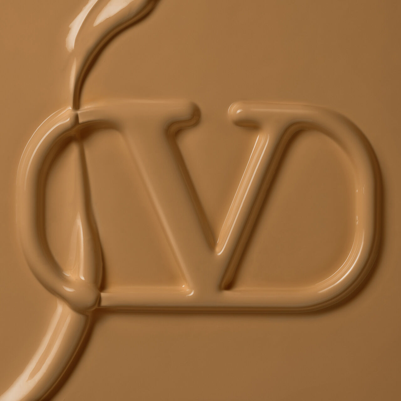 Close-up of a smooth, caramel-colored surface with an embossed logo featuring the letters "J" and "D" intertwined.