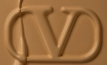 Close-up of a smooth, caramel-colored surface with an embossed logo featuring the letters "J" and "D" intertwined.