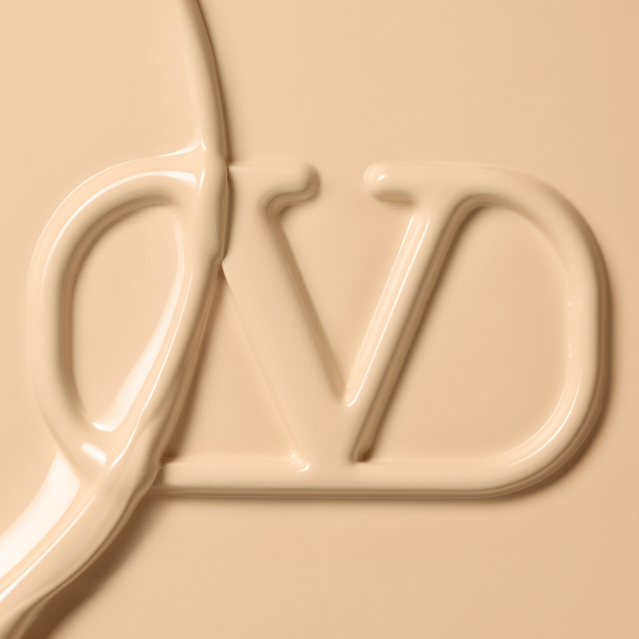 A close-up image of a creamy, beige substance shaped into the letters "D" and "V" against a smooth, neutral background.