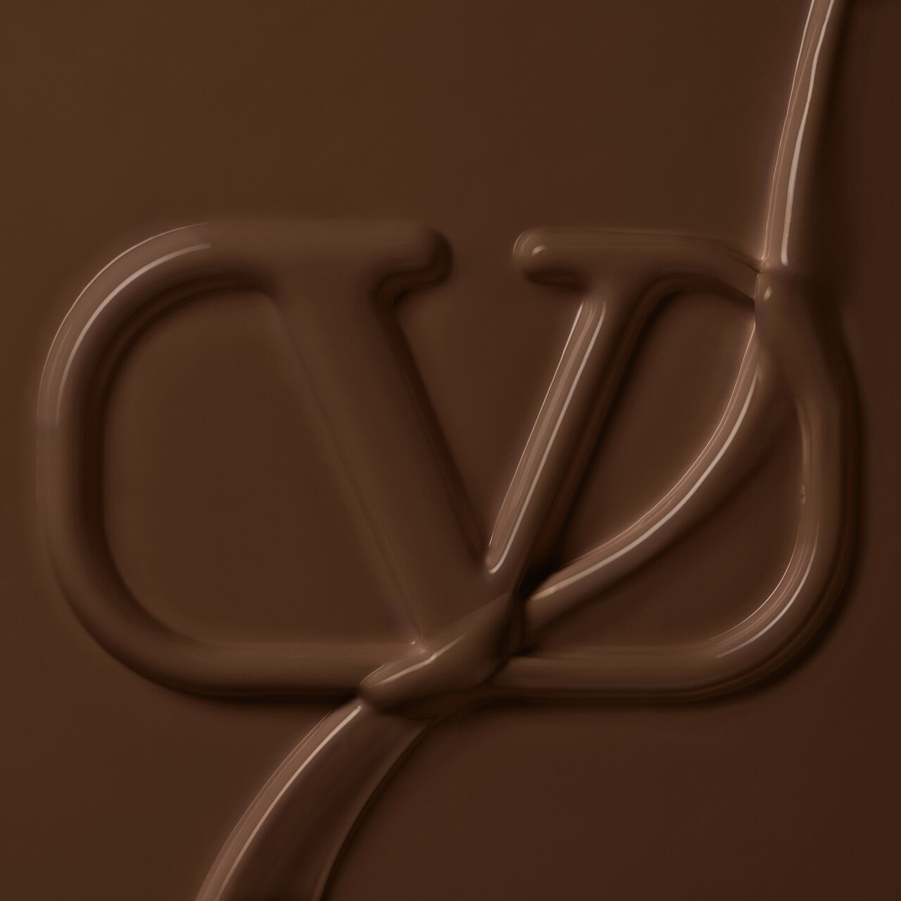 A close-up of a smooth, melted chocolate surface with a stylized logo imprinted in it. The logo features the letters "CD" intricately designed in a flowing, chocolate-like texture.