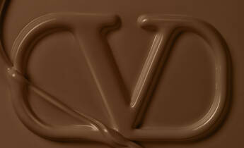 A smooth, rich chocolate background featuring an artistic, fluid representation of the letters "CD."